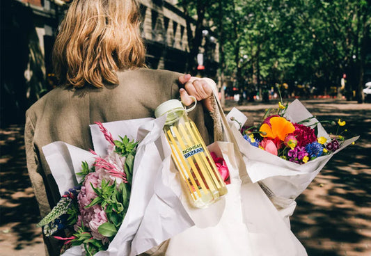 A woman holding flowers and a customized MiiR bottle
