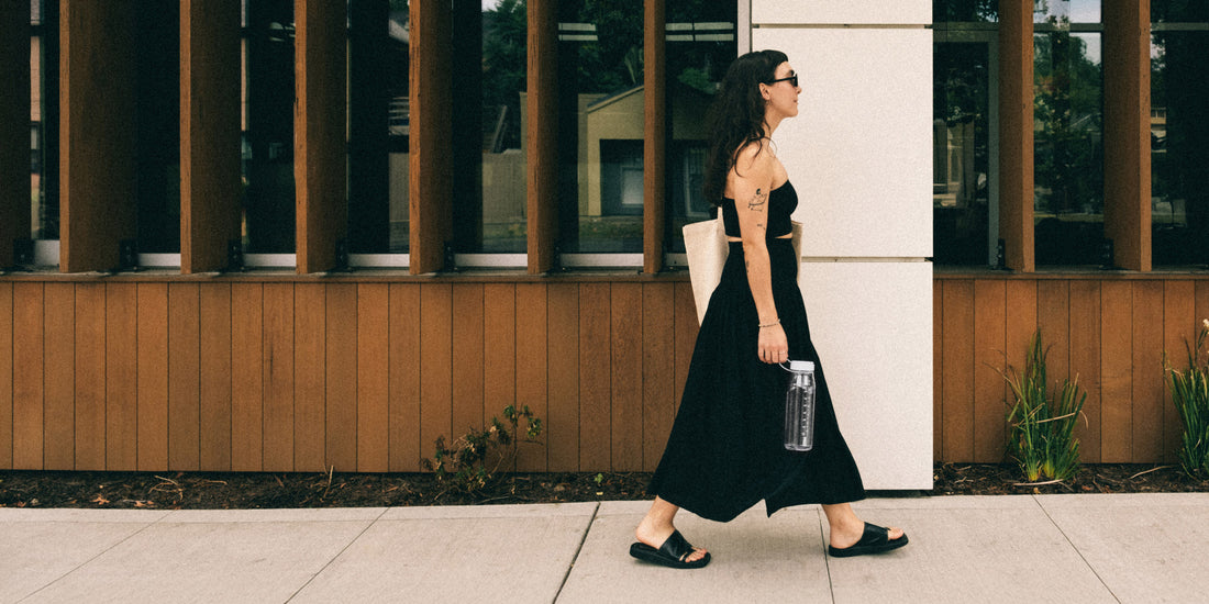 A woman walking on the sidewalk holding a MiiR Everywhere Bottle