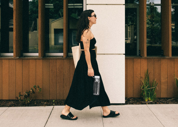 A woman walking on the sidewalk holding a MiiR Everywhere Bottle