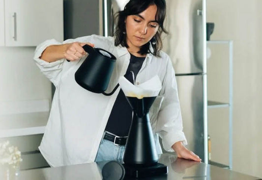 A woman making coffee using the MiiR New Standard Carafe
