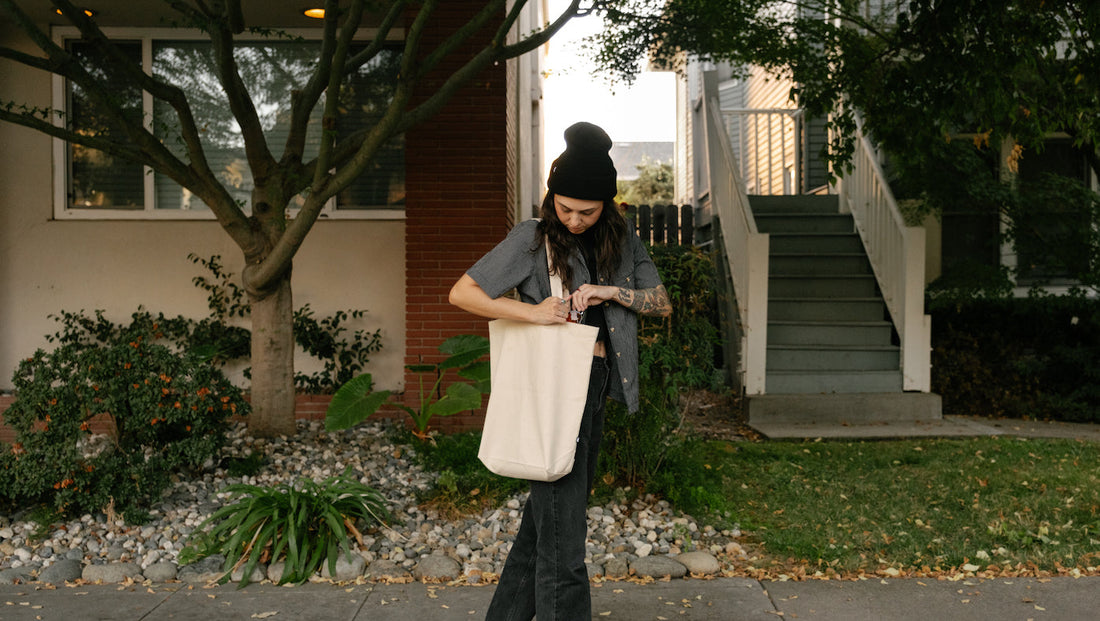 woman wearing MiiR Cashmere Beanie, looking into MiiR Everyday Tote walking down sidewalk
